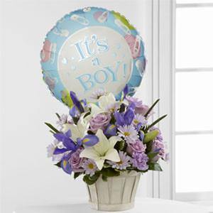 Bouquet with lavender roses, blue iris, lilies, carnations, daisies, and It’s a Boy balloon in white woodchip basket.