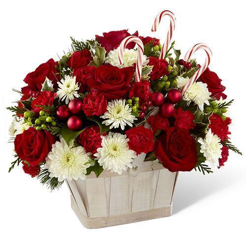 White wash basket with red roses, mini carnations, white chrysanthemums, holiday greenery, and candy canes
