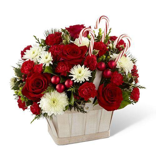 White wash basket with red roses, mini carnations, white chrysanthemums, holiday greenery, and candy canes