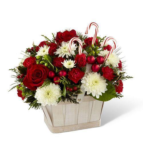 White wash basket with red roses, mini carnations, white chrysanthemums, holiday greenery, and candy canes
