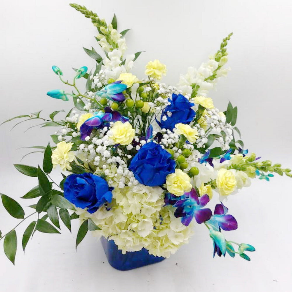 A bouquet of blue roses, hydrangea, and blue dendrobium orchids arranged in a vase.