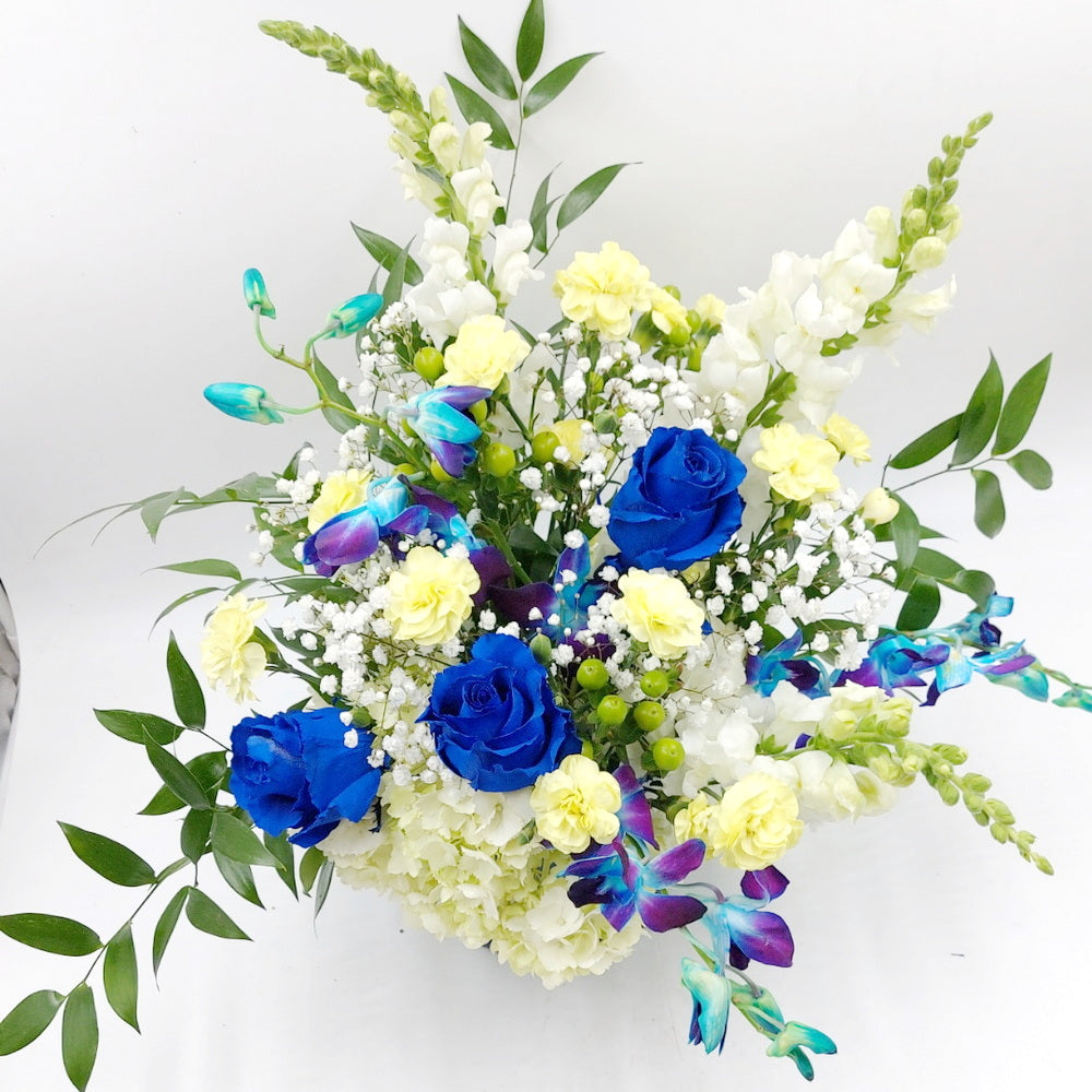 A bouquet of blue roses, hydrangea, and blue dendrobium orchids arranged in a vase.