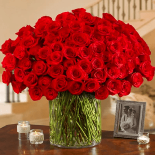 100 mixed red roses arranged in glass vase.