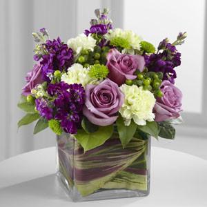 Beloved Bouquet – Lavender roses, green carnations, and purple stock in a modern glass vase.