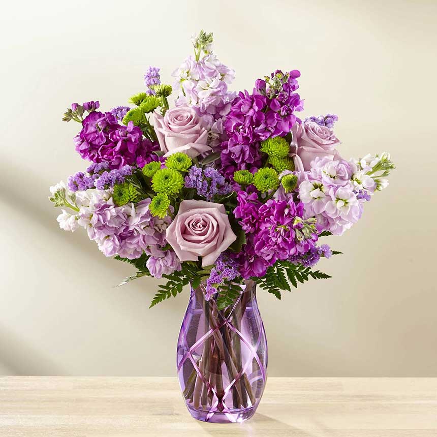 The Sweet Devotion Bouquet -  Lavender roses and purple stock flowers in a purple glass vase.