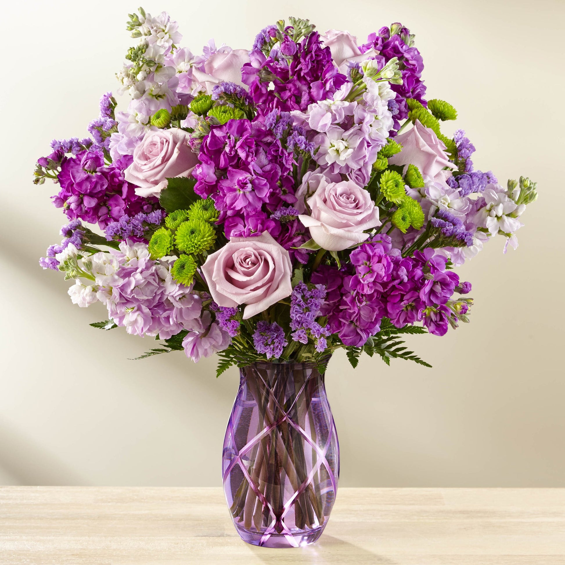 The Sweet Devotion Bouquet -  Lavender roses and purple stock flowers in a purple glass vase.