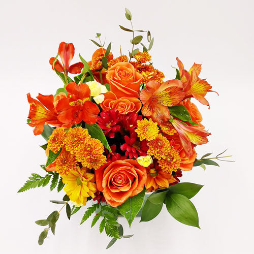 Autumn Sunset Bouquet with orange roses, daisies & alstroemeria in clear glass vase.