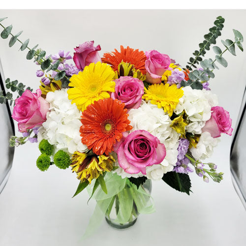 A bright floral bouquet with colorful blooms arranged in a clear glass vase, perfect for any occasion.