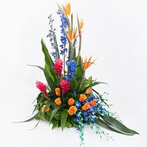 Floral tribute with birds of paradise, red ginger, blue delphinium, blue orchids, orange roses, and tropical greenery