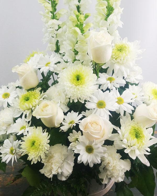 A sympathy bouquet of white roses and lilies arranged in a clear glass vase to offer comfort and peace.