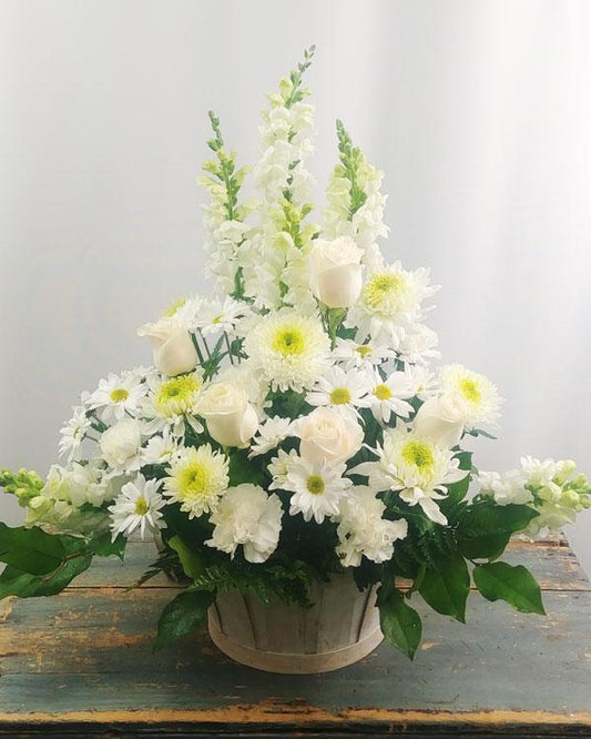 A sympathy bouquet of white roses and lilies arranged in a clear glass vase to offer comfort and peace.