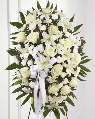 A standing spray with white roses, lilies, and chrysanthemums, elegantly arranged for funerals.