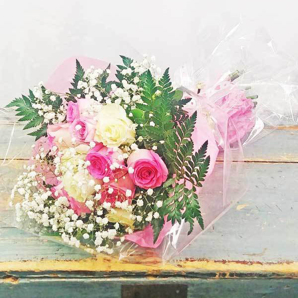 A hand-tied bouquet of pink and white roses, wrapped with baby's breath and greenery, available in 12, 18, or 24 roses.