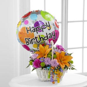 A birthday flower basket with lilies, carnations, and a Happy Birthday balloon.