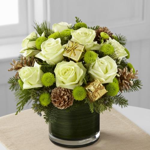 Season’s Sparkle Bouquet with jade green roses, green button poms, holiday greens, gold pinecones and mini gold gift accents arranged in a clear glass vase