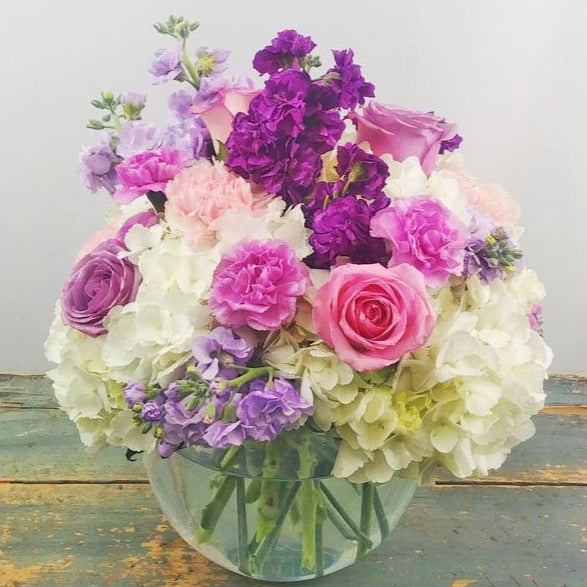 A pastel bouquet of pink roses, hydrangea, and lavender stock, accented with greenery, arranged for any special occasion.