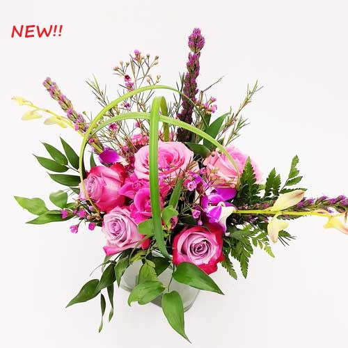 A bouquet of pink and purple roses in a modern glass vase.