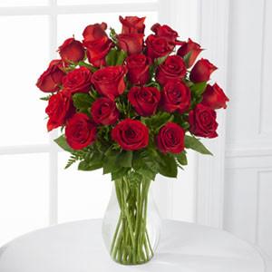 A luxurious bouquet of 24 long-stemmed red roses arranged in a classic glass vase.